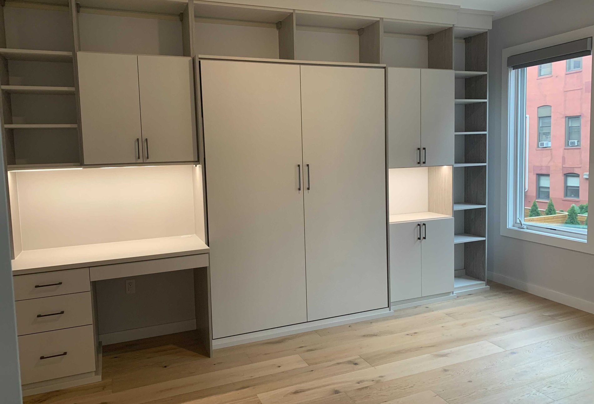 Home office with Wall Bed closed wall bed with cabinetry surrounding it with desk and integrated lighting
