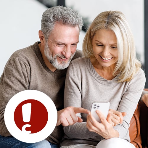 Paar sitzt auf der Couch und sieht ins Handy