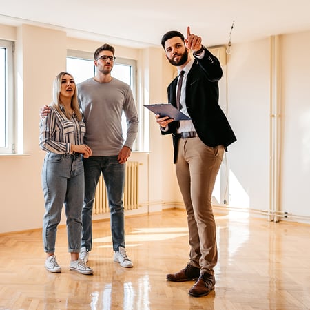 A man in a suit talking to a man and woman in an empty room