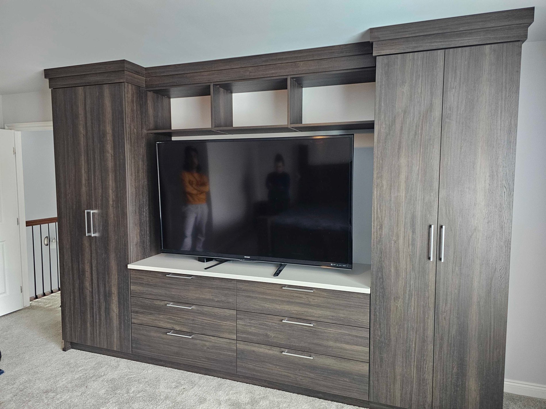 Custom Home Entertainment System Custom brown Entertainment center with a TV, has drawers, doors, and shelves