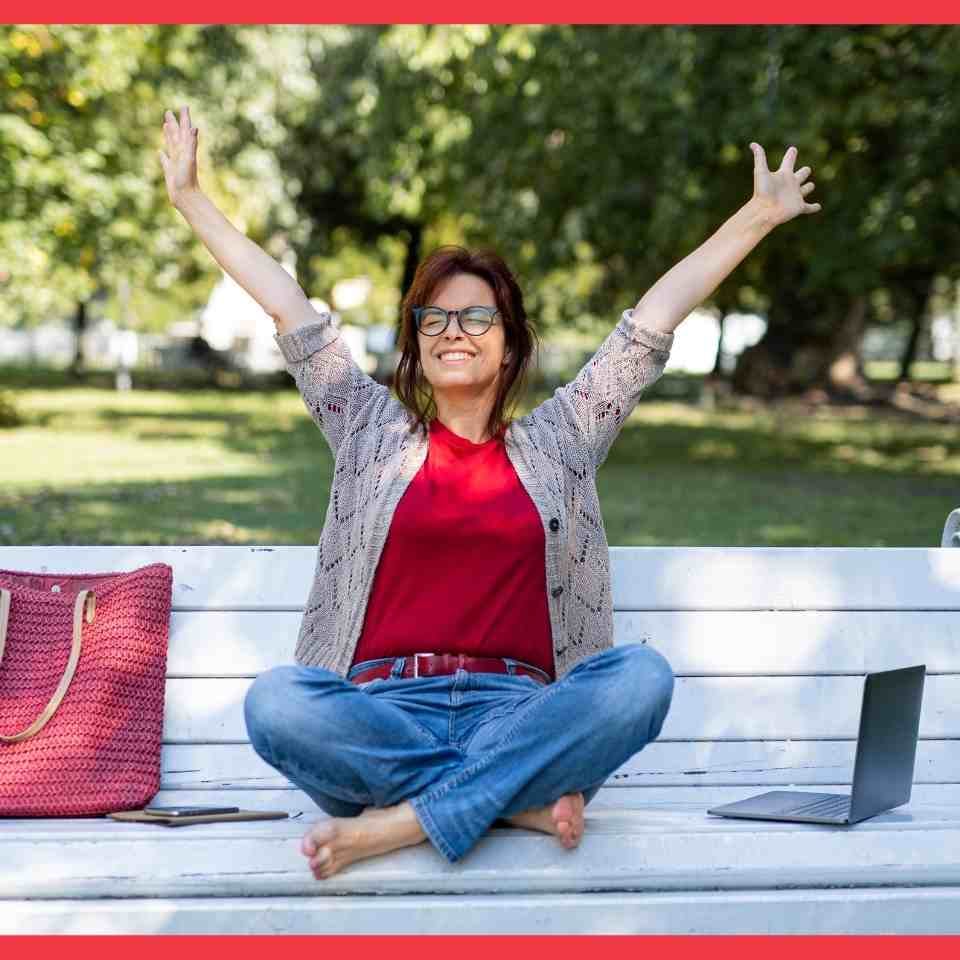 A woman on a park bench throws her hands in the air