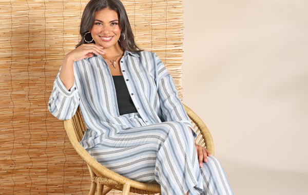 Woman is wearing a plus size linen blend matching set while sitting in a wooden chair.