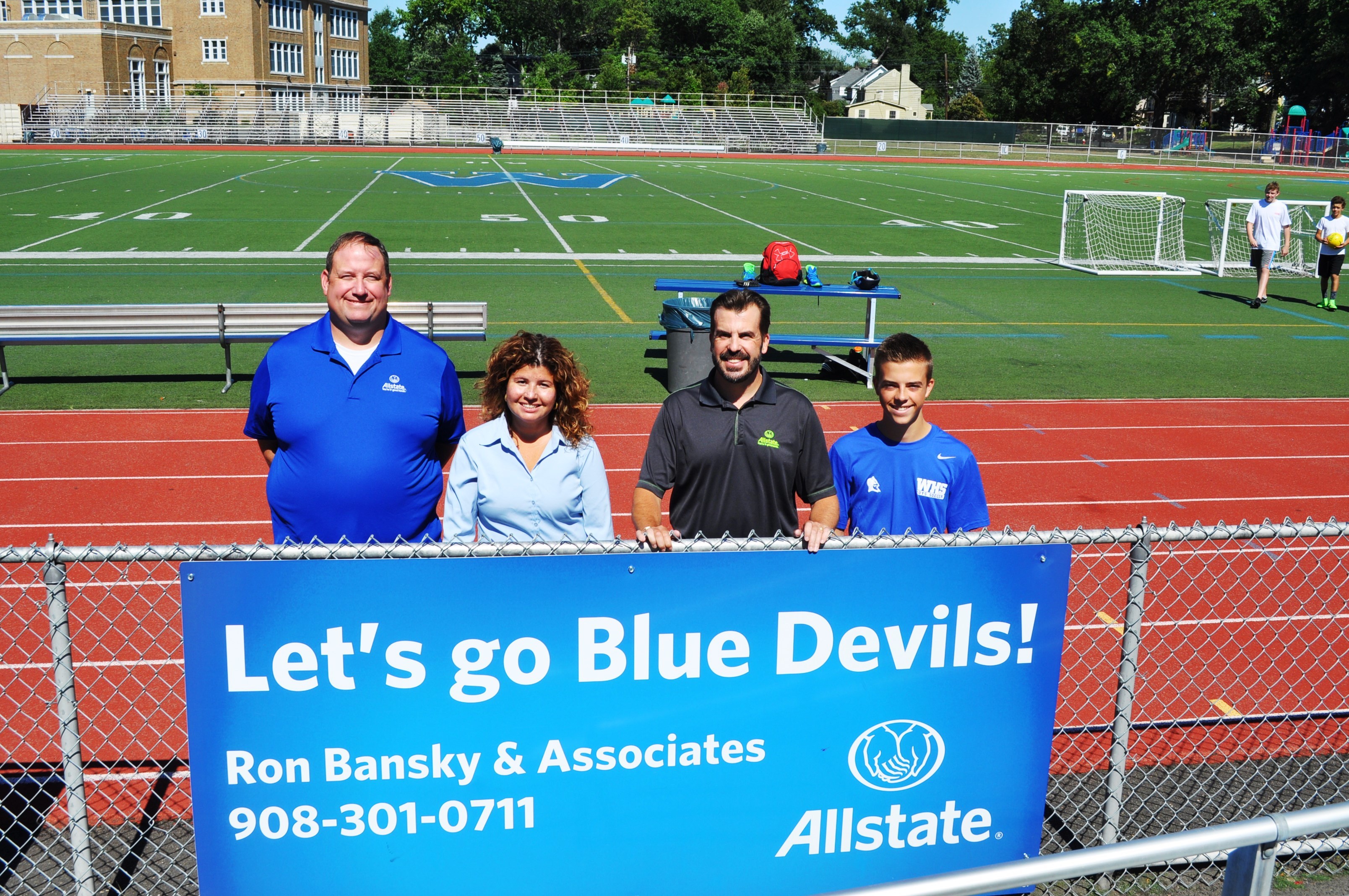 Our personal financial representative Andy Heinz, agency manager Rose Diaz, me and my son with our sign at Westfield High School's Kehler Stadium.