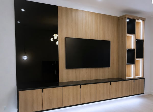 Custom media center by California Closets South Palm Beach featuring a modern built-in entertainment center with warm wood cabinetry, floating storage cabinets, floor-to-ceiling wall paneling, LED-lit display shelving, and hidden storage. Designed by Sybil Archambault, this custom living room media wall combines functional storage with contemporary design in South Palm Beach, Florida. Luxury custom media wall by California Closets featuring a built-in entertainment center, custom living room storage, floating cabinets, modern wood finishes, illuminated display shelving, hidden storage compartments, wall paneling, TV feature wall, contemporary built-in cabinetry, designer Sybil Archambault, California Closets South Palm Beach, South Palm Beach Florida, custom home organization, luxury interior design, custom cabinetry, entertainment wall.
