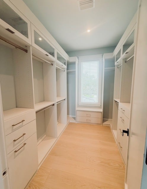 Elegant Primary Closet Custom linen primary closet with gold hardware, flip-up doors, and fluted rods.