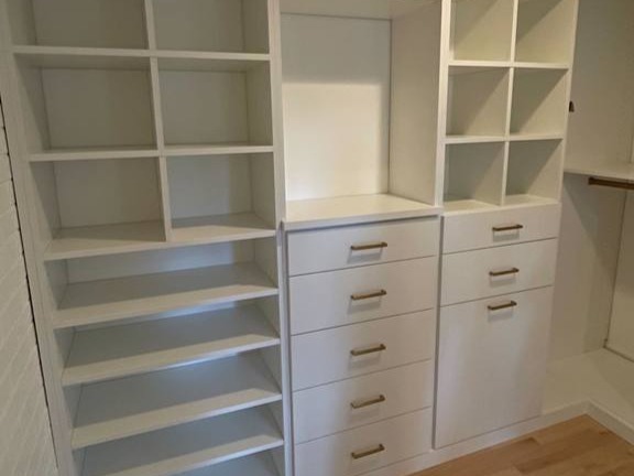 White Walk-In Closet with Shelves and Drawers Custom shelves and drawers installed in a walk-in closet.