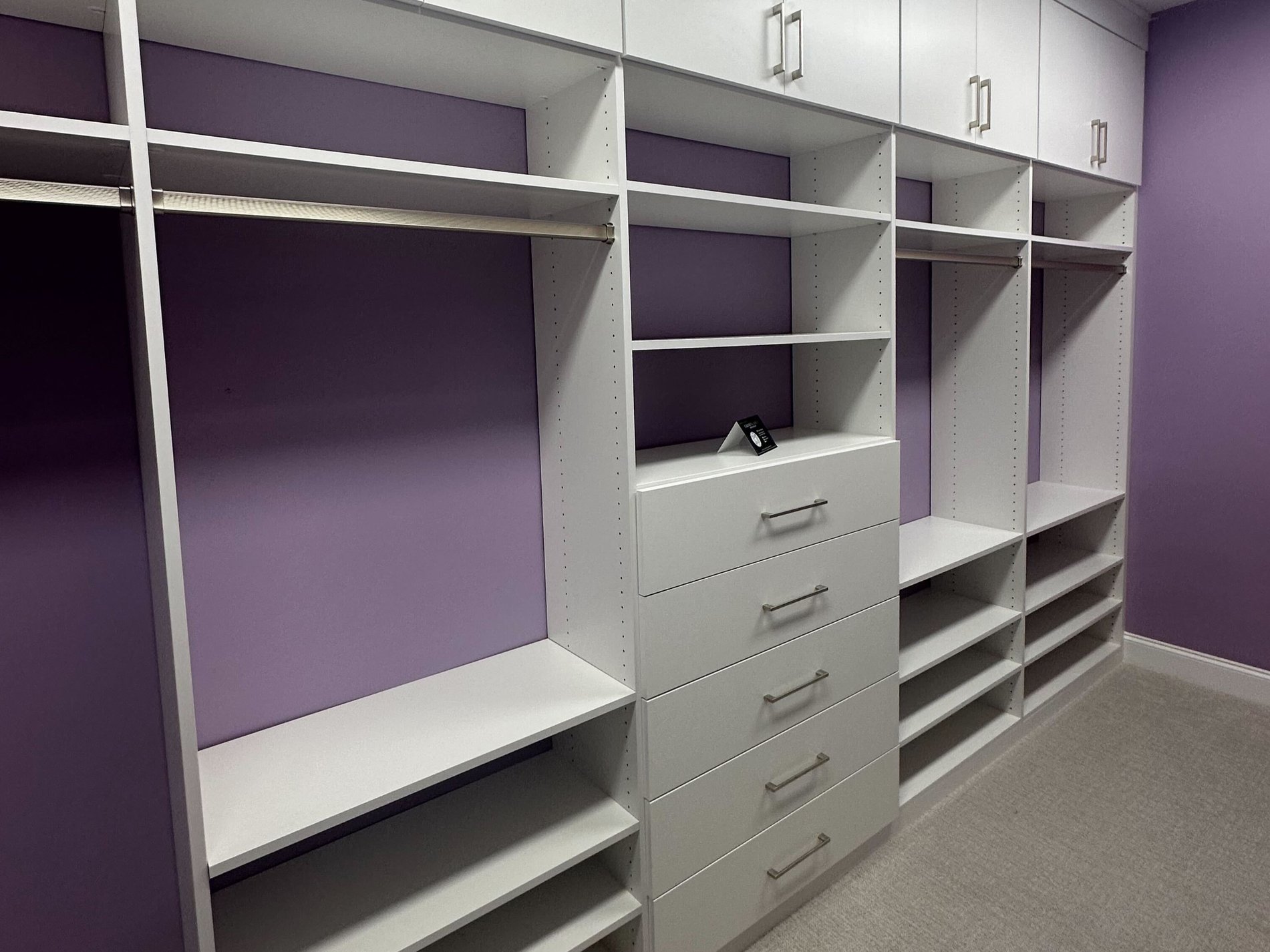 White floating media center Greensboro - Custom closets - purple walk-in closet with white shelving, clothing racks, drawers, and cabinets along the top