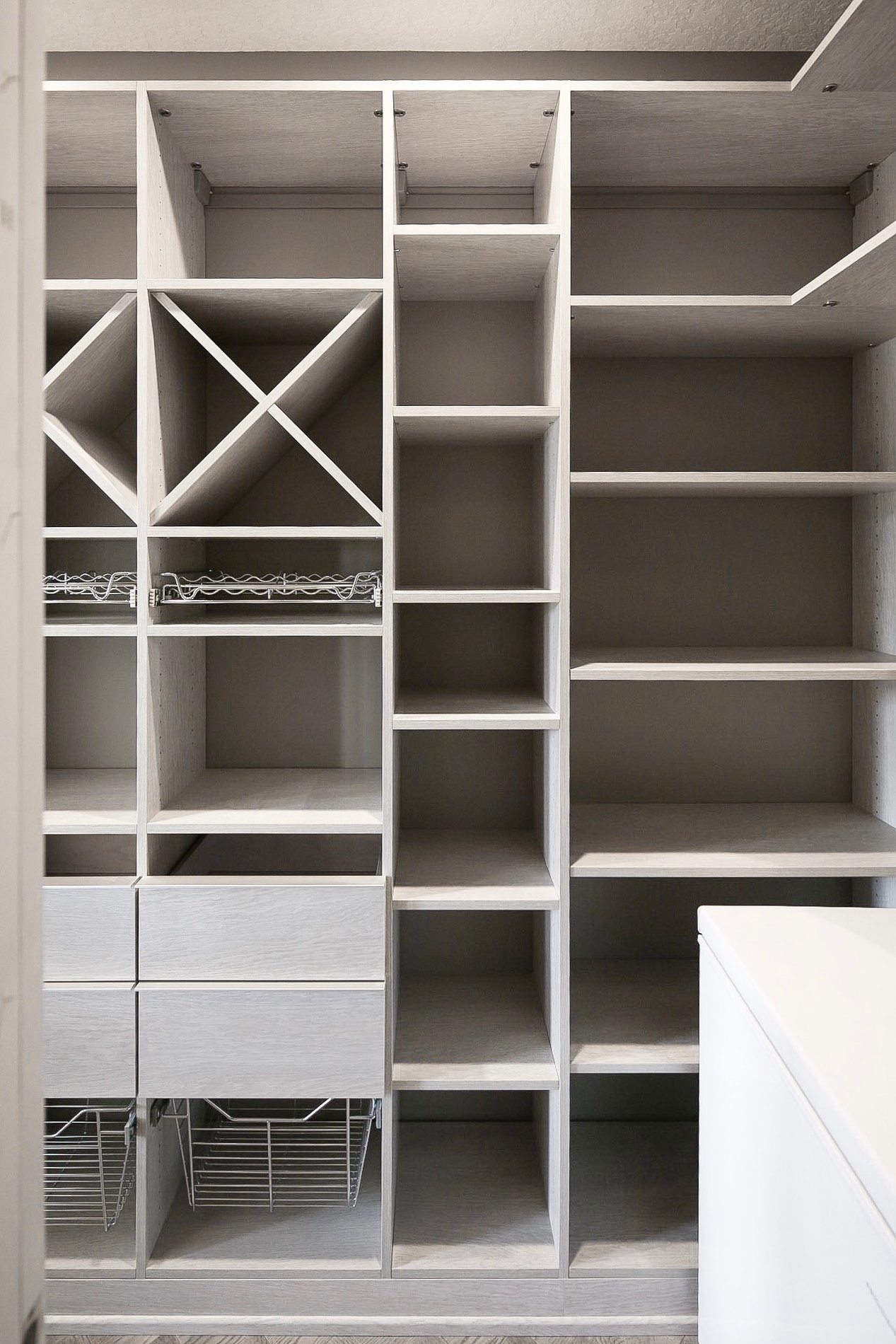 Walk-In Pantry Walk-in pantry complete with wine storage, spice racks, drawers, and pull out baskets for produce. Designed in a light gray wood grain finish.