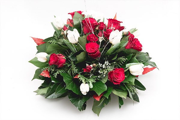 A posy of red roses and white lilies arranged into a classic floral tribute