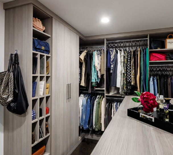 Light Gray Closet Img 6 California Closets Westchester County NY Gray Walk-in Closet Full Room Dressing Room with Double Hanging Dedicated Shoe Wall with Lighting and a Center Island with Black Leather Jewelry Drawers