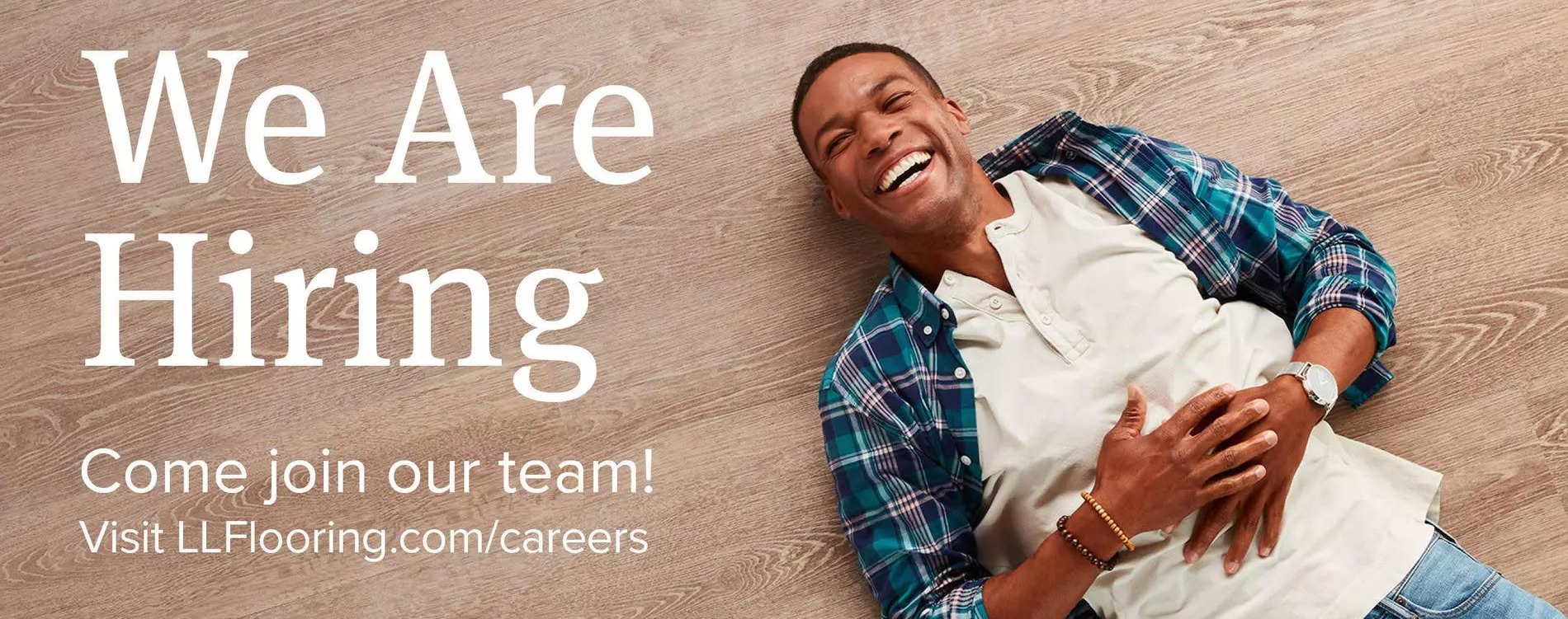 We are Hiring. Come join our team! Visit llflooring.com/careers. Man lying on hard surface floor.