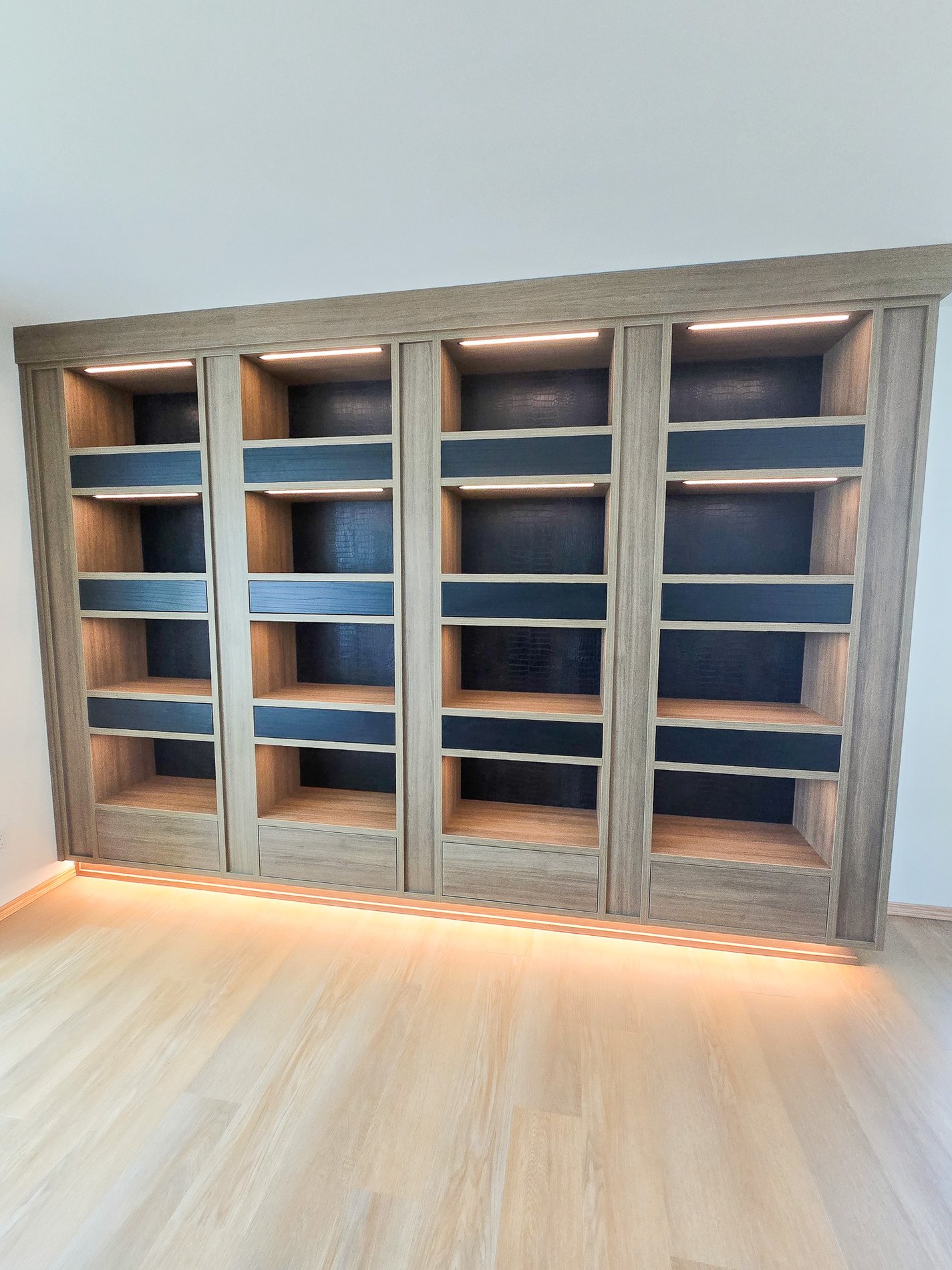 Moderna and Masculine Bookcase Modern and masculine book case designed in a mid tone wood grain finish with dark black accents and lighting.
