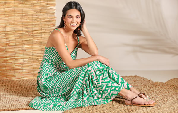 Woman wearing a green and white maxi dress is sitting on the floor.