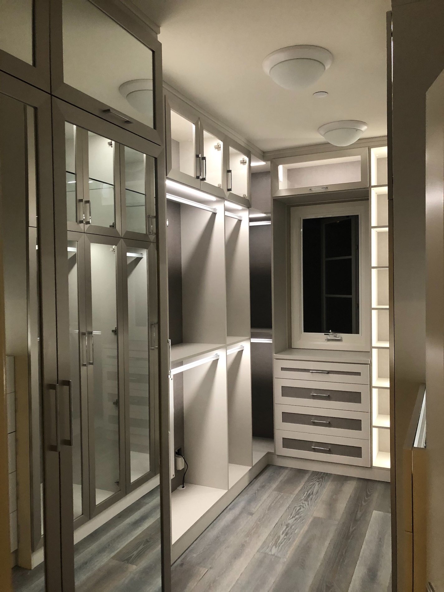 White and grey walk-in closet with mirrored doors and lighting Custom built walk in closet