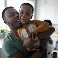 An African American dad lifting his son in his arms