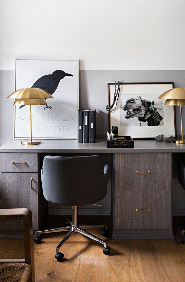 Modern work space with dark framed art Dark home office desk with various framed paintings
