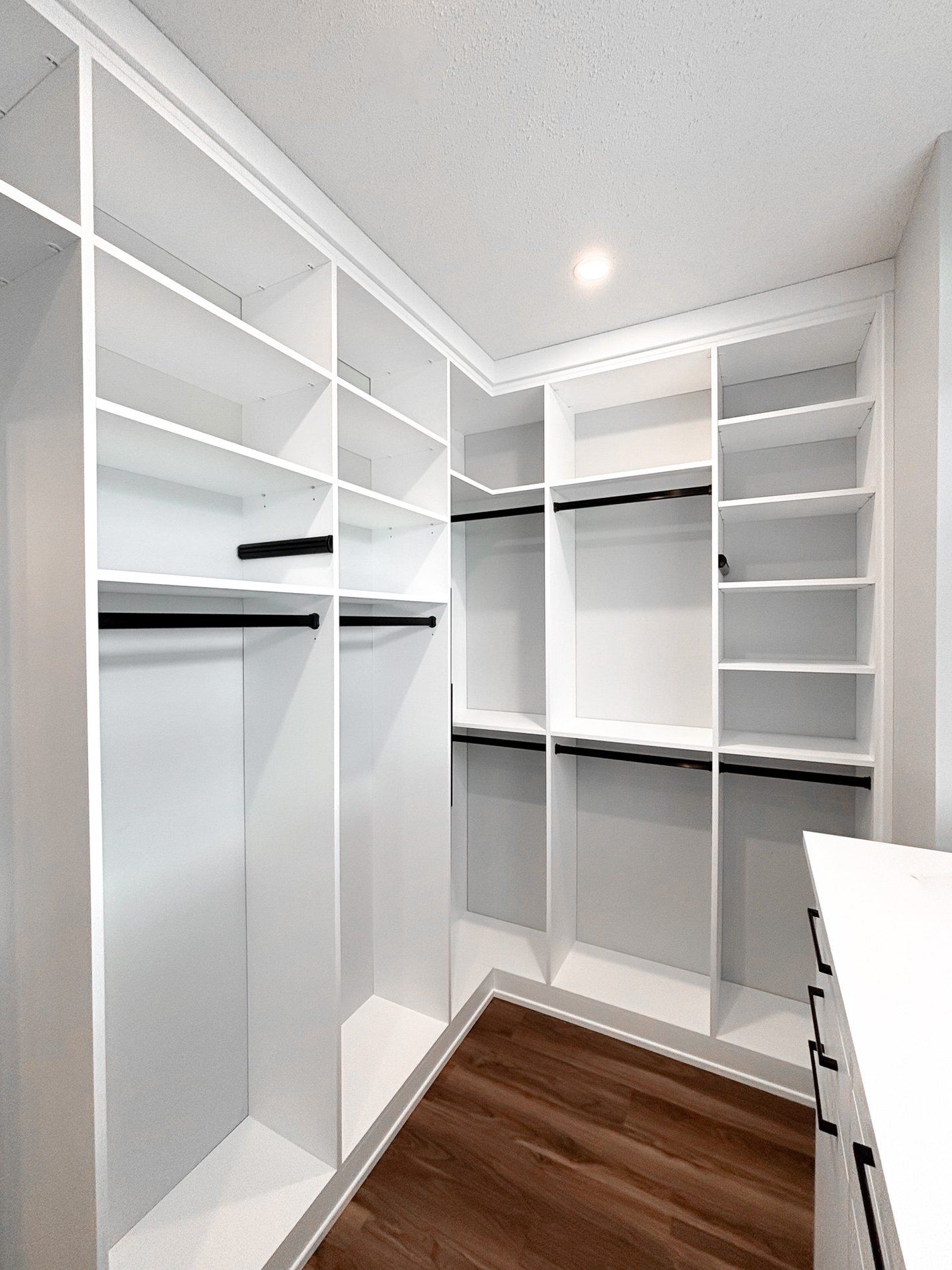 Bright and White Walk In Closet White walk in closet with black hardware and drawers under a window.
