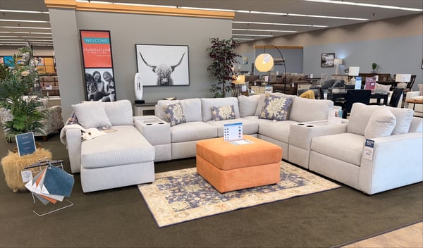 Discover unbeatable comfort and style at Slumberland Furniture Burlington, your trusted local furniture store serving Burlington, Iowa, and surrounding areas like Fort Madison, Mount Pleasant, and Southeast Iowa. Featured here is our customizable modular sectional sofa with chaise, shown in a soft ivory performance fabric—perfect for large living rooms, family rooms, or open-concept spaces. This sectional includes built-in cupholders, storage consoles, and plush, reversible cushions for long-lasting comfort. Paired with a bold orange storage ottoman and a transitional-style area rug, this display showcases our mix of traditional and modern design elements. Looking for deep-seated couches, family-friendly sectionals, or custom fabric options for sofas in Burlington, IA? We offer financing with no promo fees, interest-free monthly payment plans, and flexible delivery options, including full-service setup. Whether you're browsing for farmhouse furniture, modern sectional couches, or living room sets on sale, Slumberland Burlington is your go-to destination for affordable luxury and home decor inspiration. Stop by today or call us for current deals on high-quality, customizable furniture built to last.
