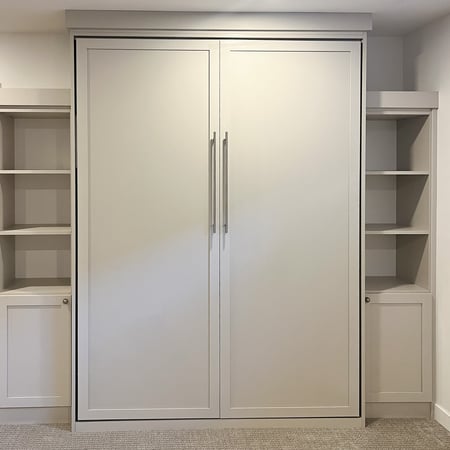 Simple off white wall bed with closed and open shelving on the sides.