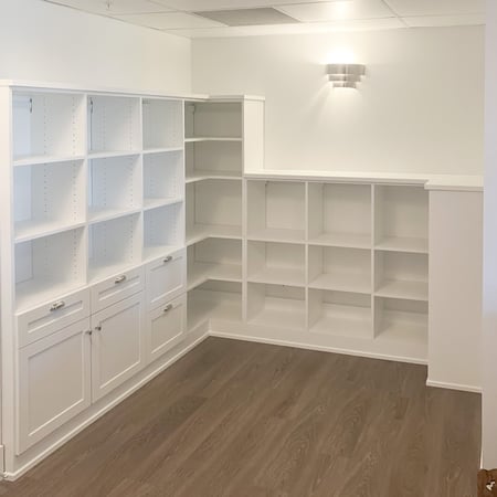Corner library in white with mostly open shelving and a few closed cabinets.