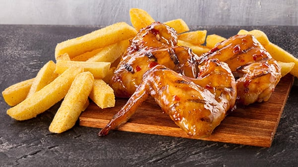 Flame-grilled chicken wings and small hand-cut chips from Steers® on a wooden board.