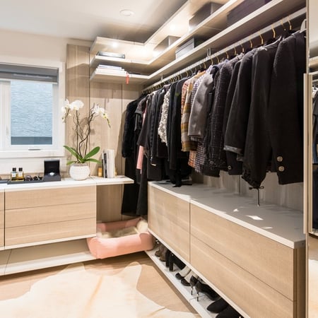 Modern walk in closet with floating shelves and drawers.
