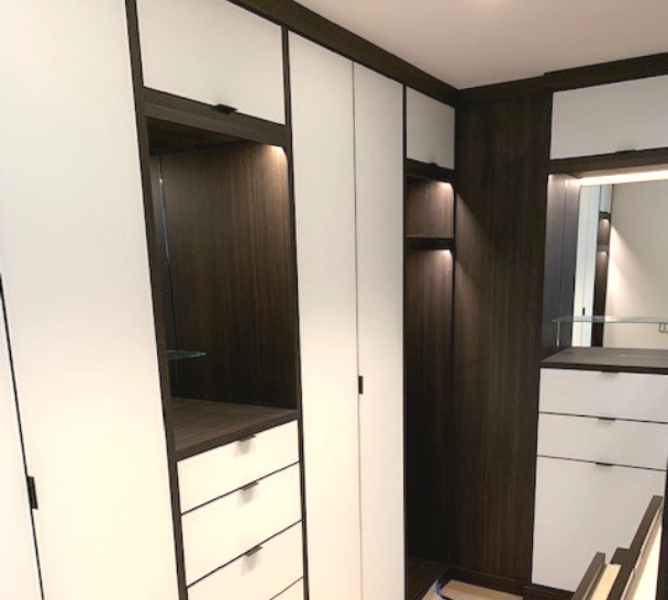 dark brown & white walkin closet with closed cabinetry, drawers, vanities and LED lighting