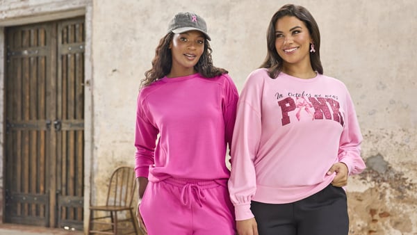 Two women are wearing pink outfits for Breast Cancer Awareness Month.