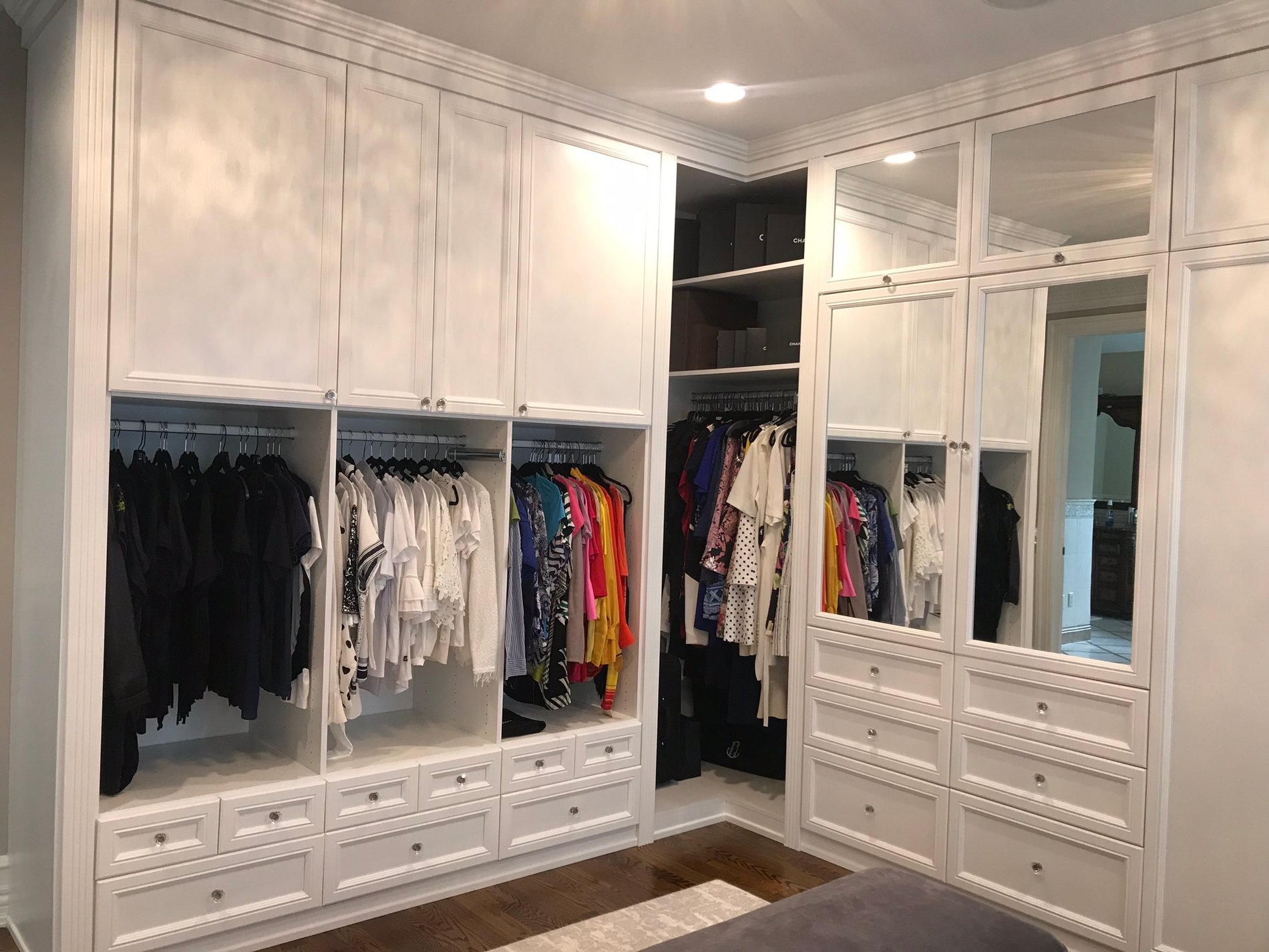 large white wardrobe with doors and drawers and hanging clothing with mirror