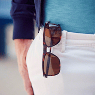 Designer sunglasses hanging in woman's pocket