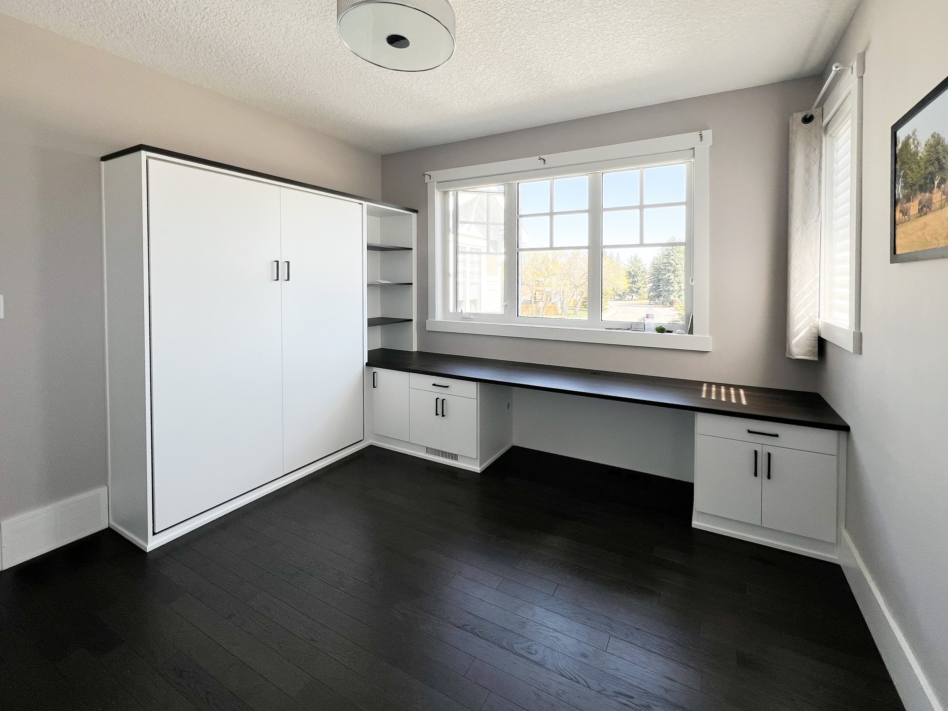 White and black home office with a wall bed.