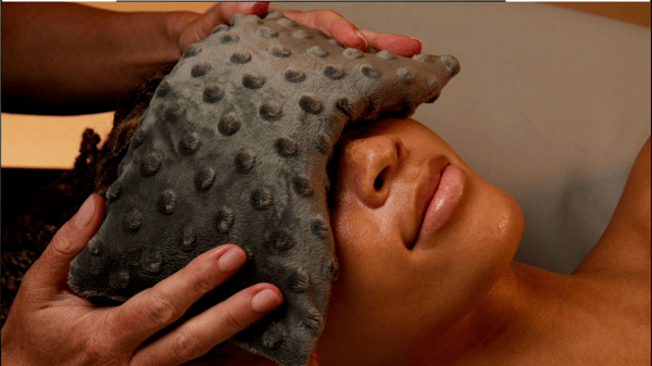 Eye pillow being placed gently on face prior to beginning massage and facial services at Woodhouse Peachtree City