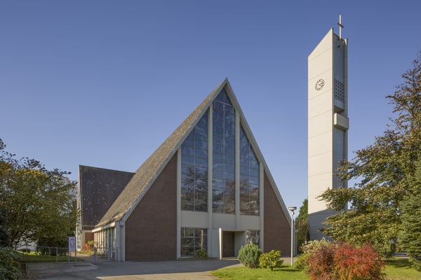 Das moderne, dreieckförmige Kirchengebäude mit freistehendem Glockenturm.