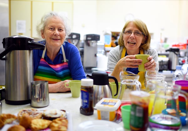 Two ladies smiling as they have breakfast