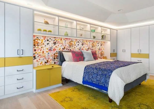 bedroom with built-in cabinets in white and yellow with a bed and colorful wallpaper