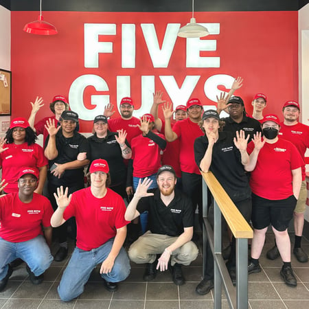Employees pose for a photograph in front of the queue ahead of the grand opening of the Five Guys restaurant at 1008 East Battlefield Road in Springfield, Missouri.