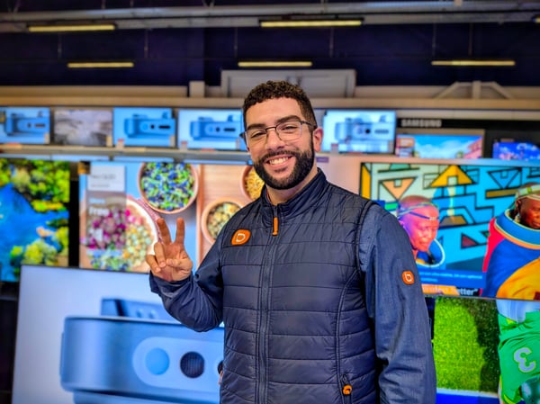 Mohand conseiller de vente du magasin boulanger persan chambly, qui pose devant le rayon des téléviseurs 55 pouces.