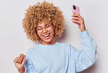 woman with curly hair holding a cell phone