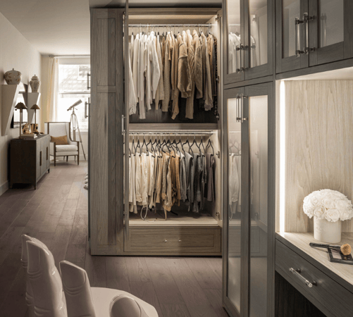 luxury gray wardrobe walkin closet with color coordinated clothing, double hanging with doors open, doors have frosted glass, LED lighting, vanity and crystal hardware Manhattan New York