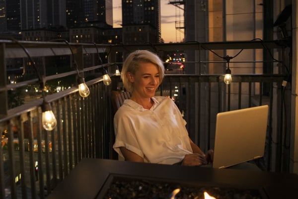 Woman on laptop sitting on balcony in Seattle using Fiber Internet