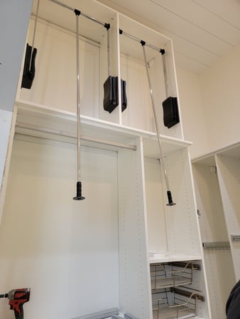 White walk-in closet with pull-down hangers and baskets