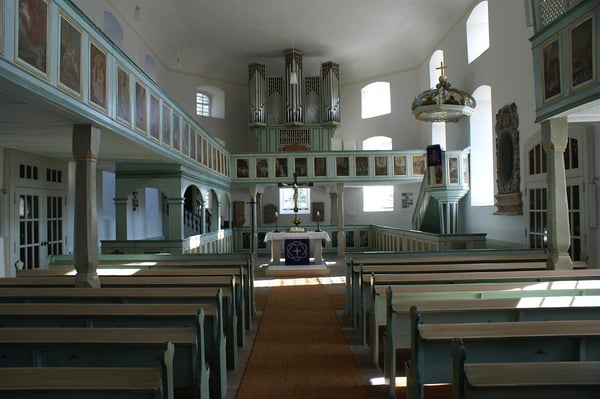 Das Bild zeigt die Evangelische Kirche Grebenau von innen. Zu sehen ist der Altar und die Orgel. Viele Verzierungen und Gemälde prägen das Gesamtbild.