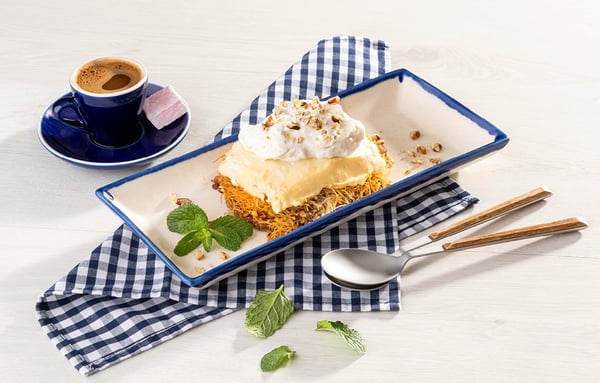 An image depicting a dessert on a plate, made with layers of whipped cream, custard and pastry.