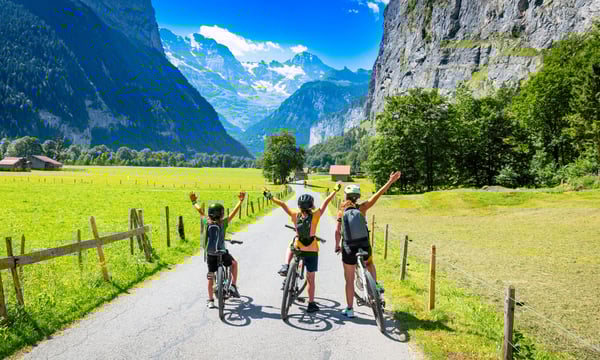 自転車で山間いを旅する家族の後ろ姿