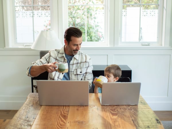 Dan y su hijo usando una computadora portátil en la mesa de la cocina