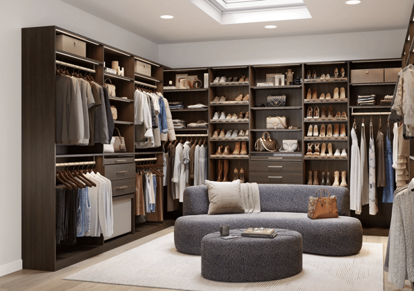 Custom walk-in closet design by California Closets San Antonio, featuring adjustable shelving, ample shoe storage, drawers, integrated lighting, and a luxurious dark woodgrain finish.