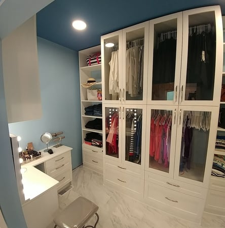 White Walk-in closet with glass doors and built-in vanity