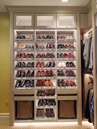 Built-in storage shelves filled with shoes and pull-out hampers