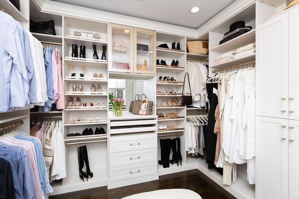 Light finish walk-in closet with floor to ceiling storage, glass cabinet doors with lighting by California Closets, Greenwich, Connecticut.