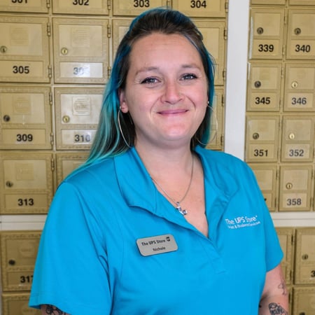 Smiling female associate standing in front of mailboxes at The UPS Store